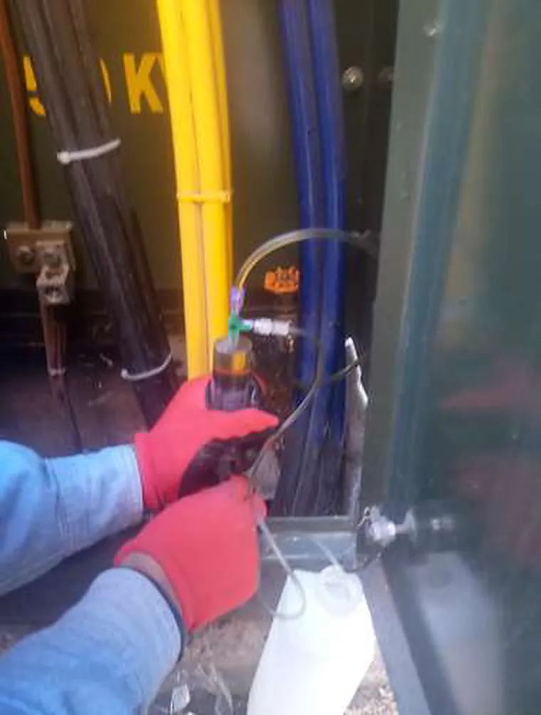 Técnico con guantes tomando una muestra de aceite de un transformador para laboratorio