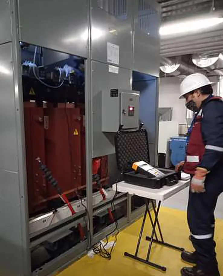 Técnico junto a un transformador seco realizando la prueba de resistencia de aislamiento