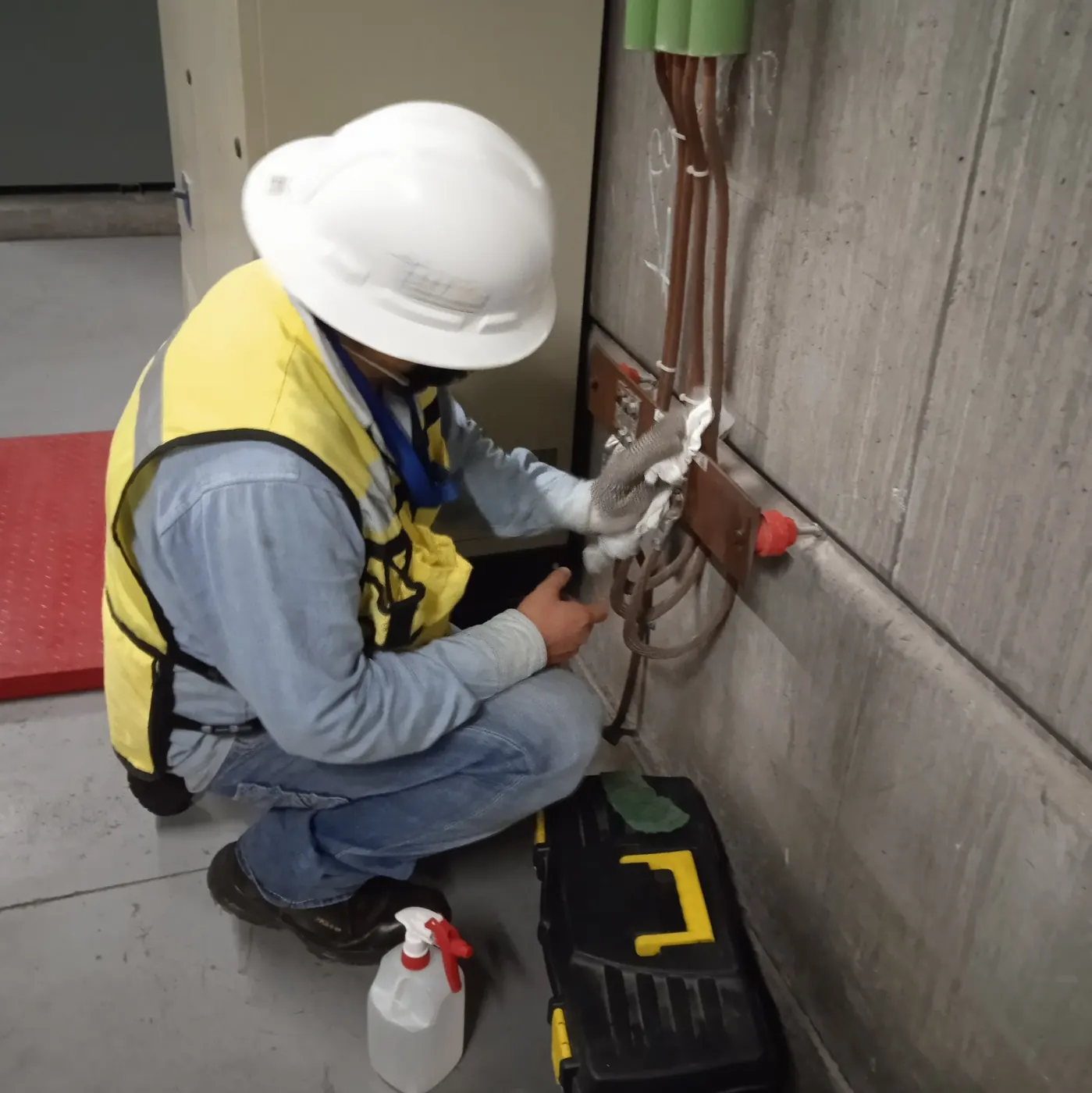 Técnico revisando la conexión de un conductor de puesta a tierra a una barra de cobre