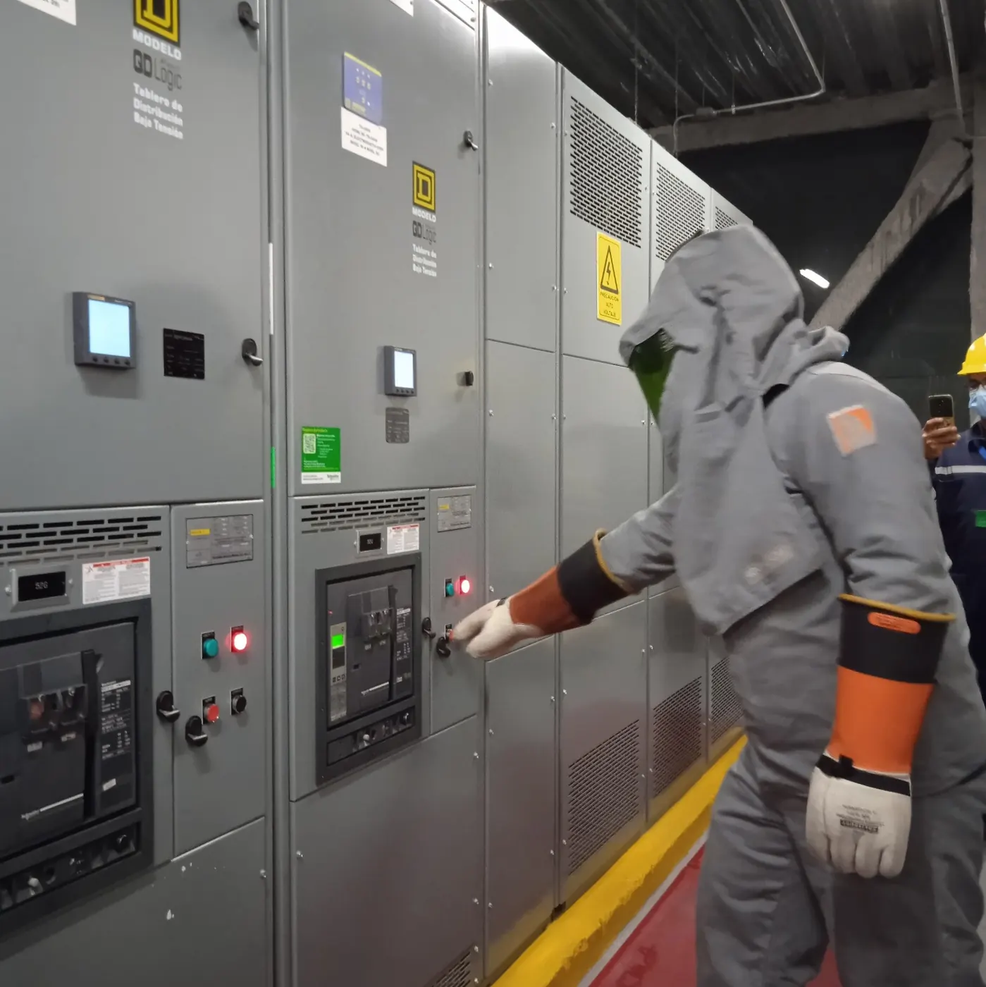 Técnico con traje de protección operando un tablero de distribución de baja tensión