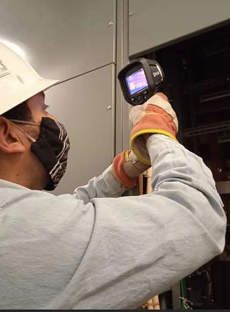 Técnico apuntando una cámara termográfica a un tablero eléctrico